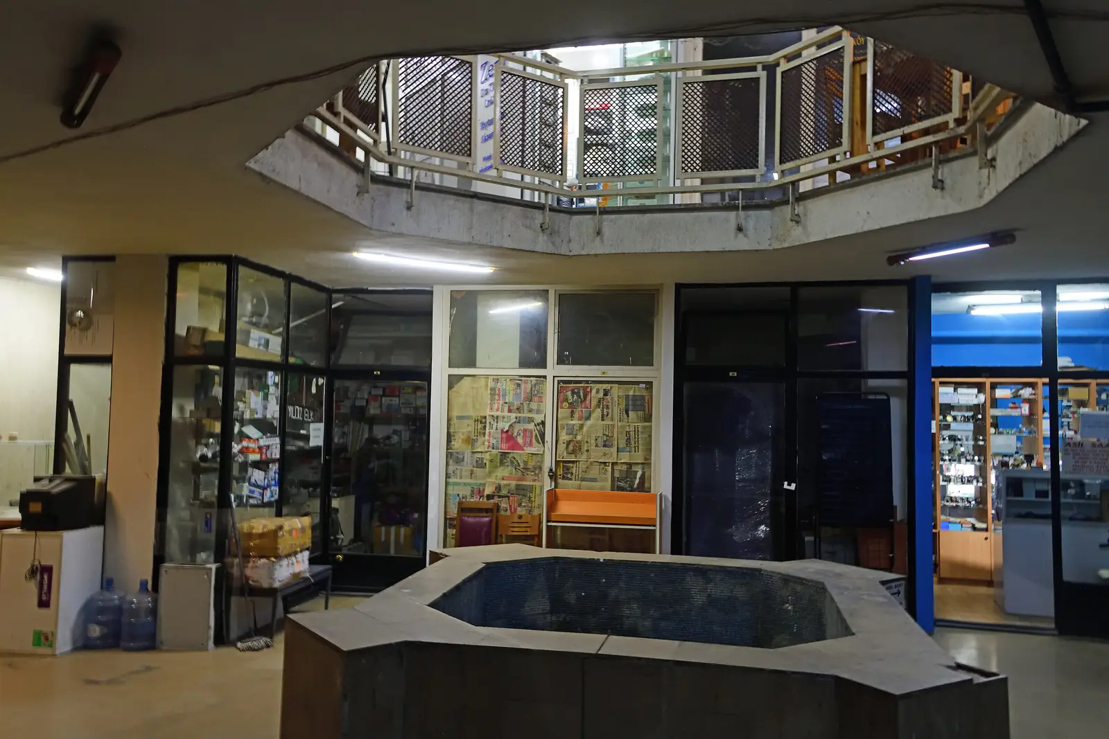 A stone basin in the middle of a hall in the old hamam, with a gallery rail and a dome above